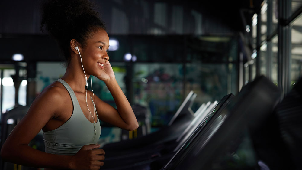 Žena bežiaca na bežeckom páse s drôtovými slúchadlami_02