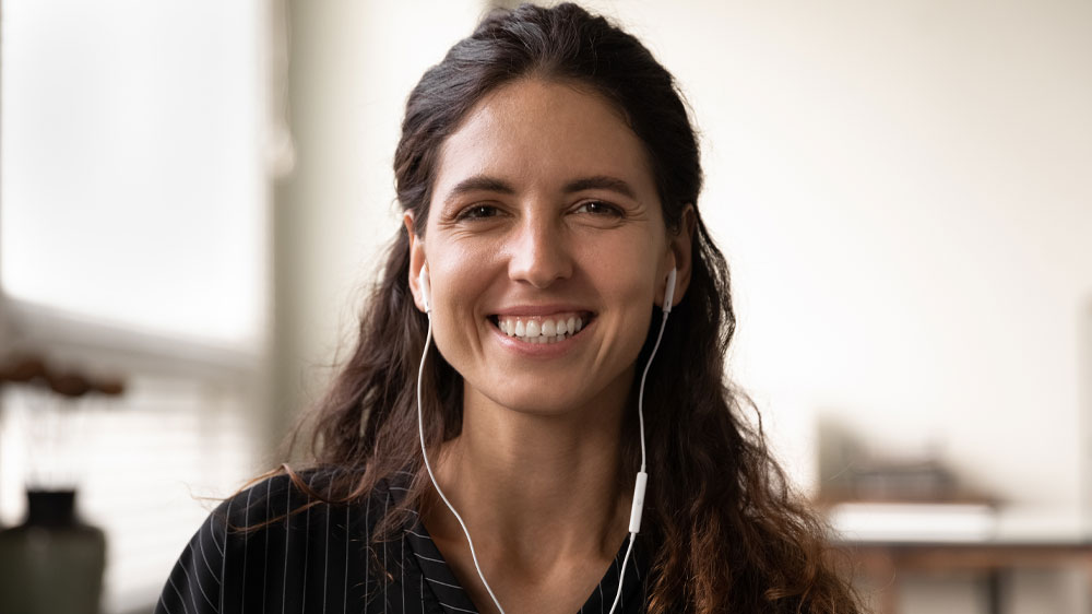 Usmievajúca sa žena s drôtovými slúchadlami v ušiach_03