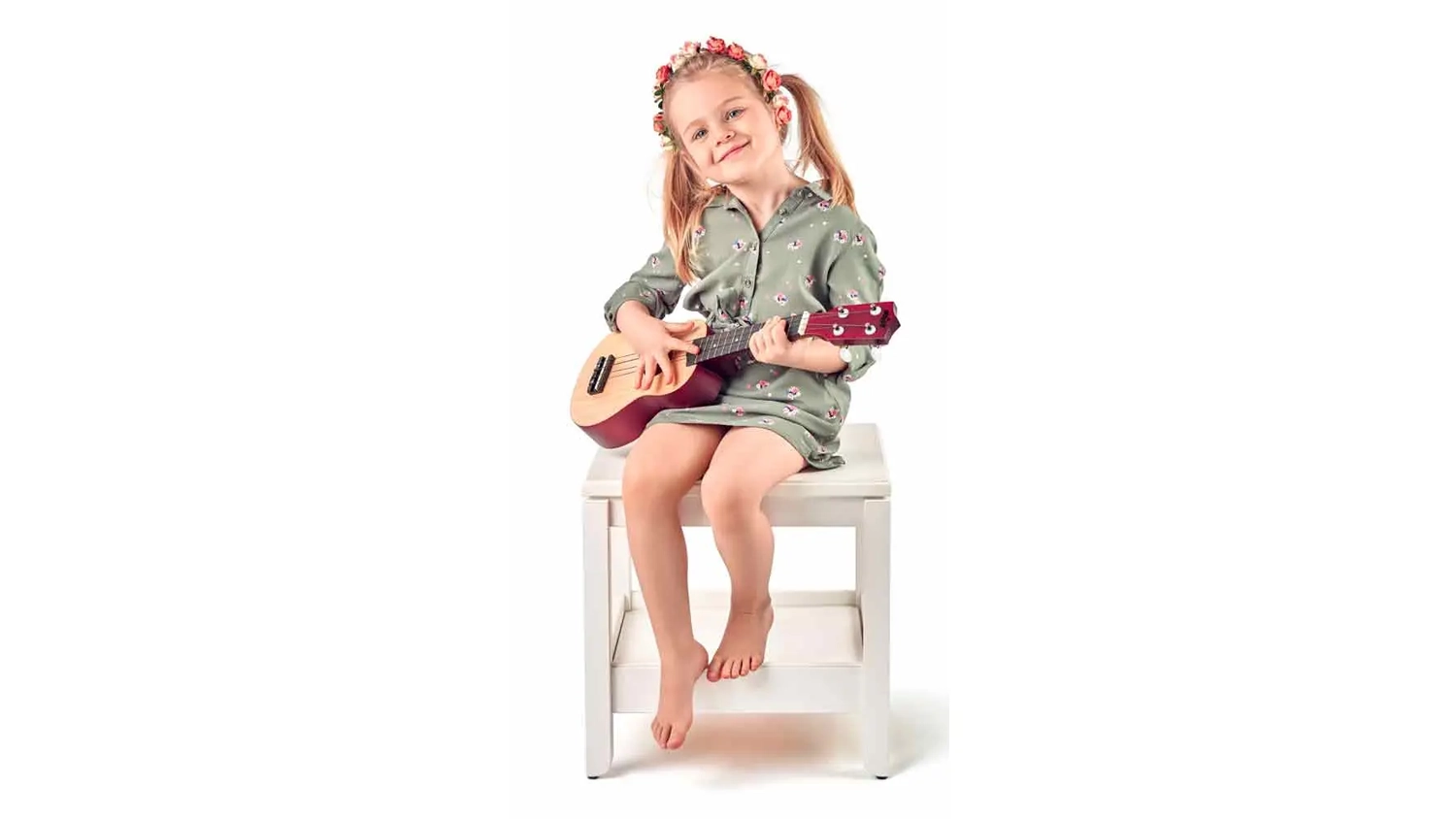 Holčička sed&iacute; na stoličce a hraje na ukulele