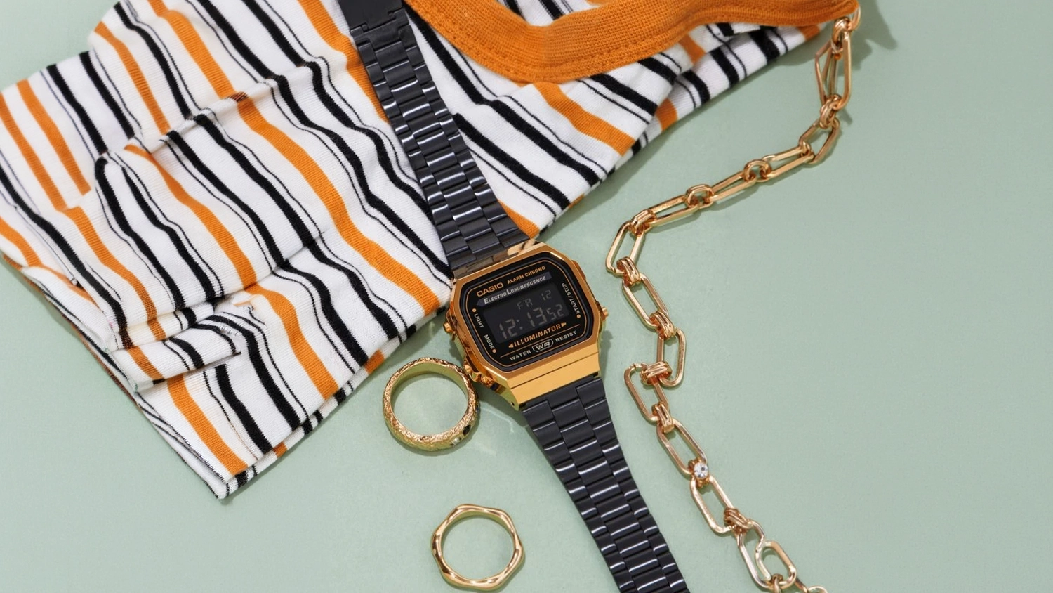 Unisex náramkové hodinky Casio A168WEGB-1BEF Vintage Iconic se šperky na stole