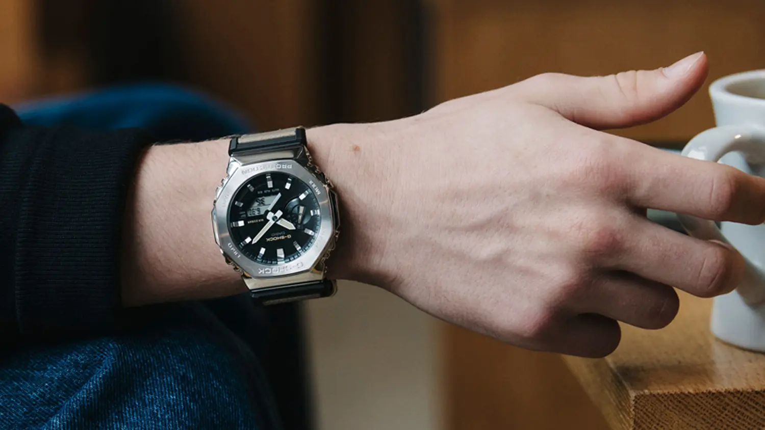 Ruka s hodinkami Casio G-SHOCK GM-2100C-5AER držiaca pohár