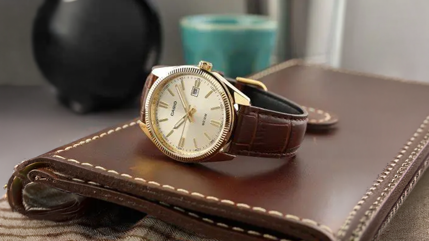 P&aacute;nske n&aacute;ramkov&eacute; hodinky Casio MTP-1302PGL-9AVEF položen&eacute; na koženom denn&iacute;ku
