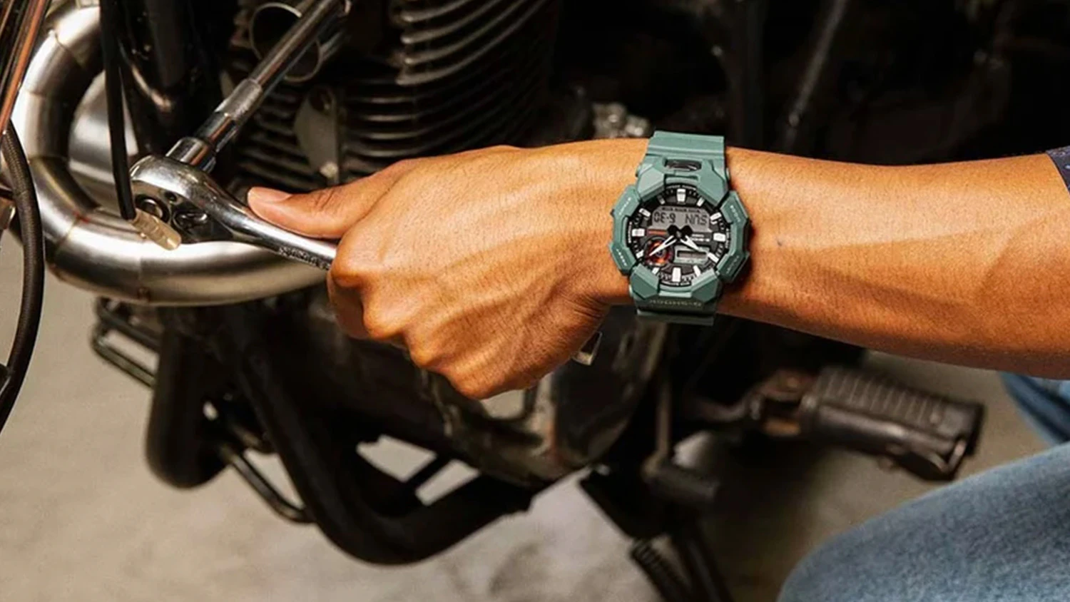 mužsk&aacute; ruka s hodinkami Casio GA-010-2AER G-SHOCK opravuj&uacute;ca motor motocykla