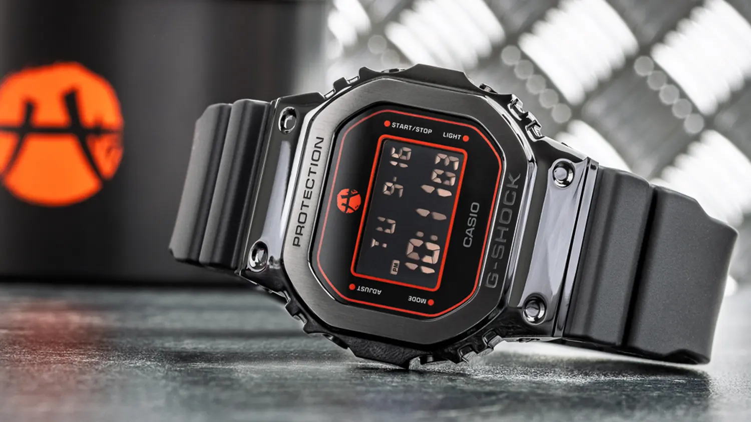Pánské náramkové hodinky Casio GM-5600RH-1ER< položené na stole.