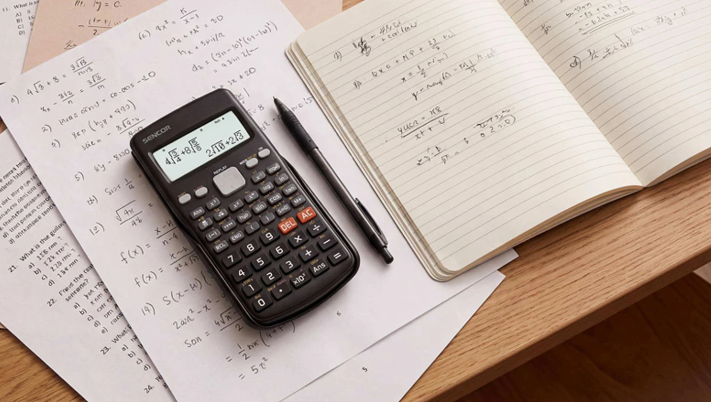 Vědecká kalkulačka SENCOR SEC 190 na popsaném sešitě vedle učebnic, pera a notebooku