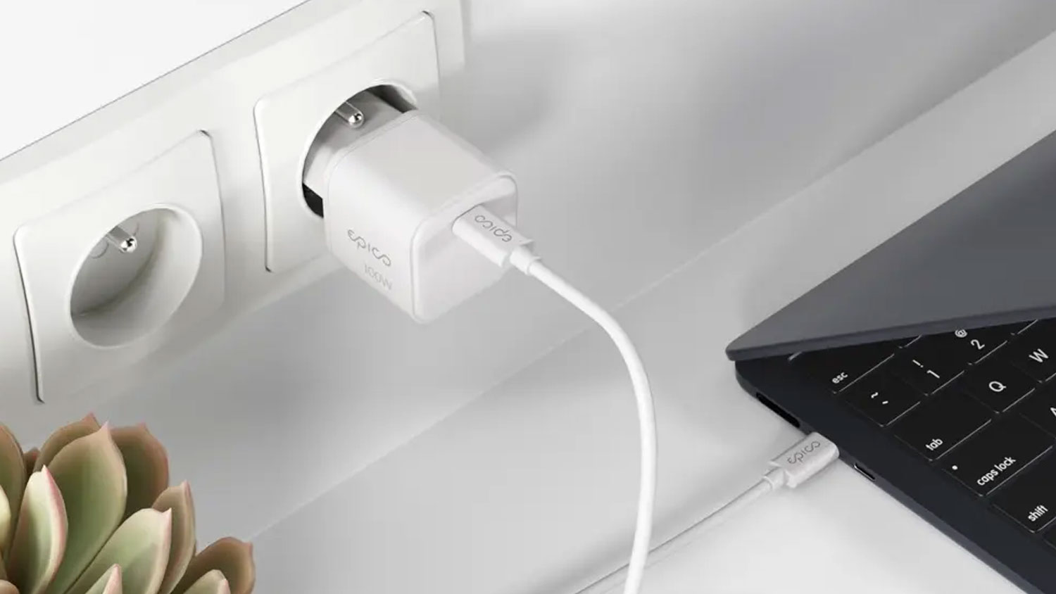 Bílý nabíjecí adaptér Epico zapojený do zásuvky a propojený kabelem USB-C s notebookem na stole.