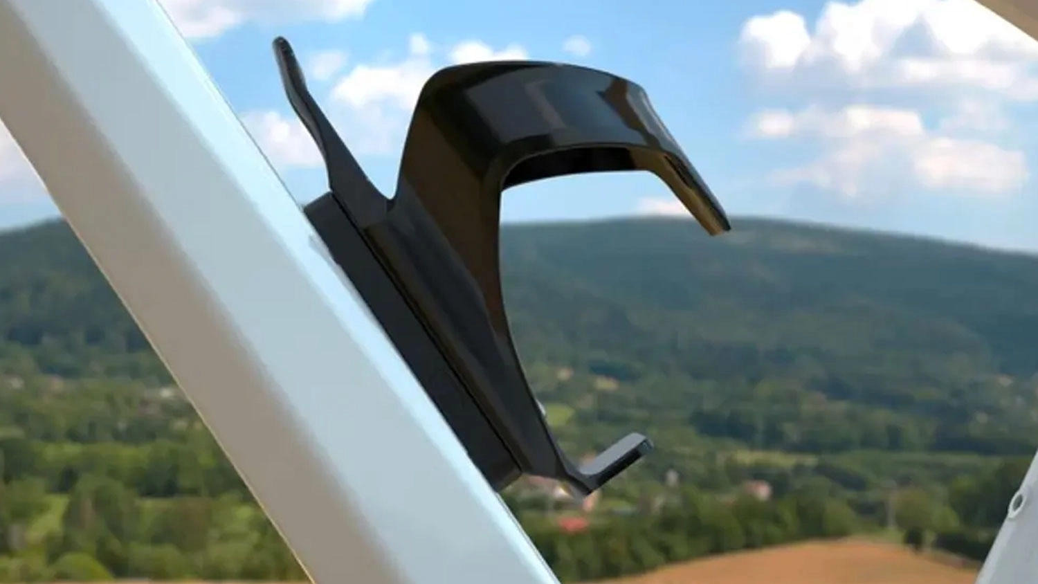 Černý lokátor FIXED Tracket Tag Bikee upevněný pod košíkem na lahev na bílém rámu jízdního kola.