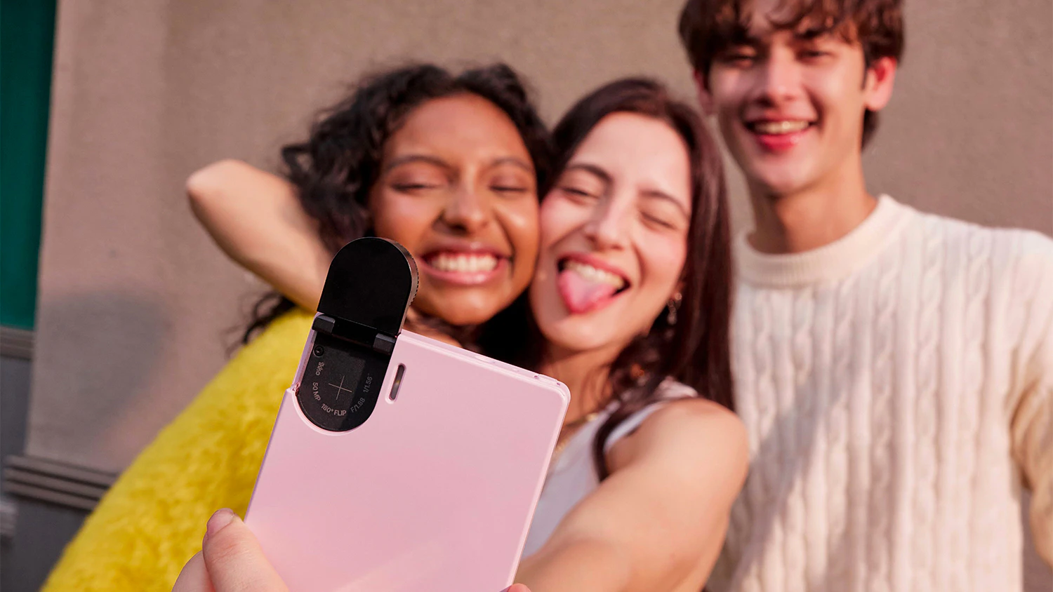 Dvě d&iacute;vky a chlapec si pořizuj&iacute; selfie s otočn&yacute;m fotoapar&aacute;tem telefonu iKKO MindOne PRO