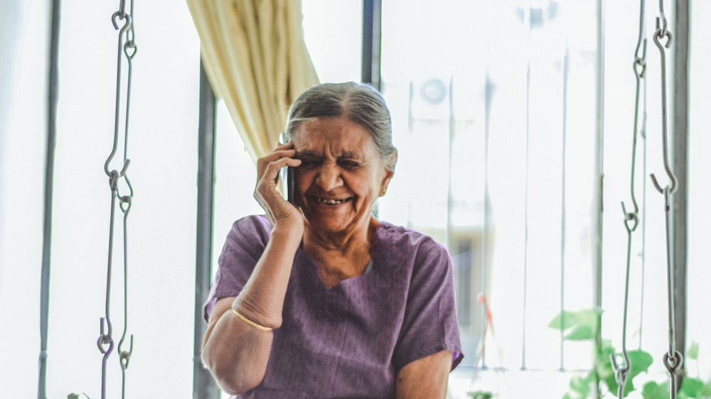Telefonující starší paní před oknem_03