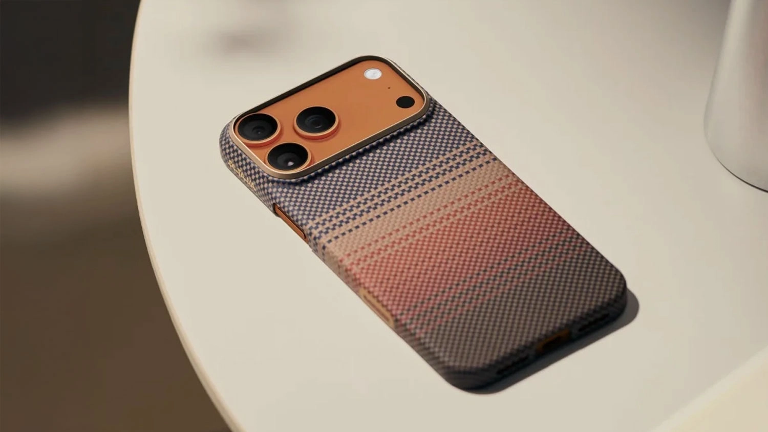 Mobil v obalu Pitaka Ultra-Slim Case položen&yacute; na stole.