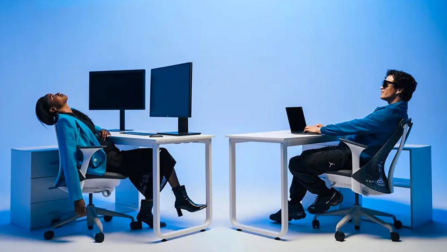 Žena pracující na monitorech a muž pracující s notebookem a chytrými brýlemi