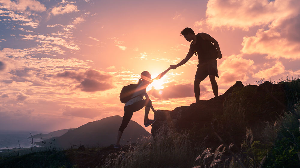 Muž pomáhající ženě vylézt na skálu_02