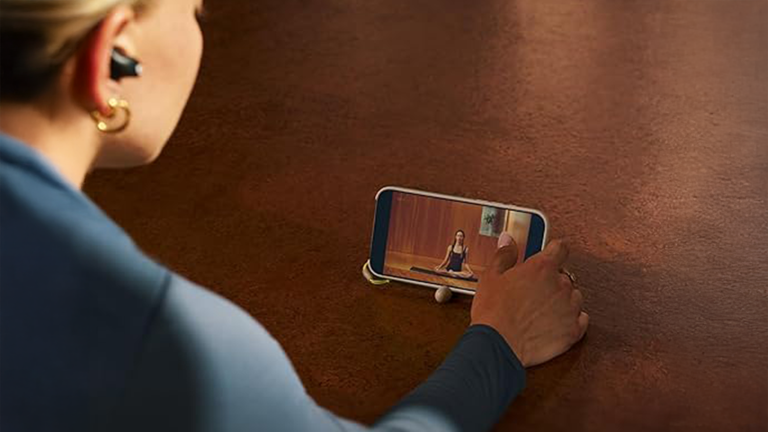 Žena sleduje video z mobilu, který je umístěný ve stojánku Kickstand Case MS + Camera Control