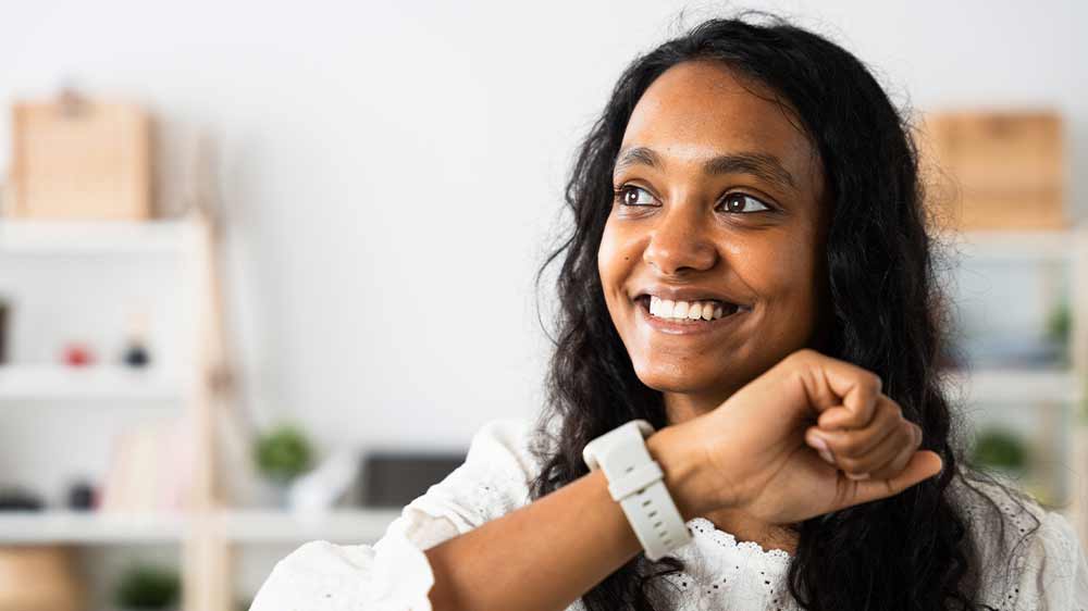 Usmívající se mladá žena telefonující přes chytré hodinky nasazené na zápěstí_05