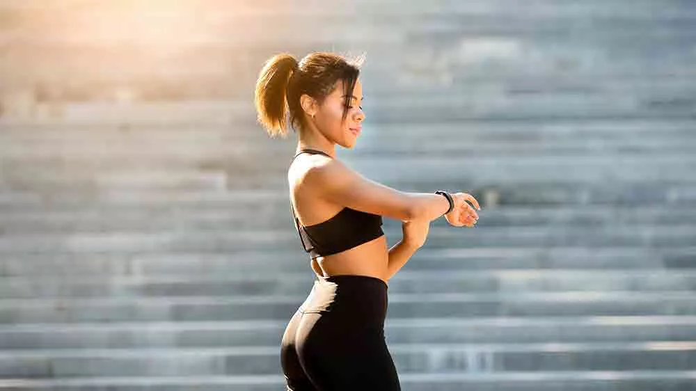 Žena ve sportovn&iacute;m oblečen&iacute; sleduj&iacute;c&iacute; fitness n&aacute;ramek na sv&eacute;m z&aacute;pěst&iacute;_03