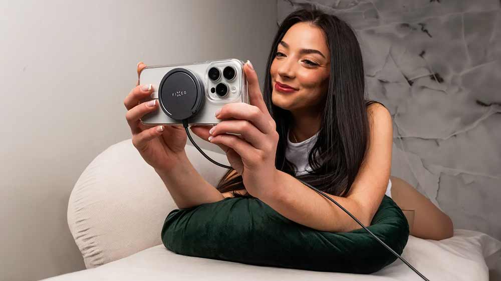 Žena držící telefon s připojenou nabíječkou FIXED MagPad Pro_02