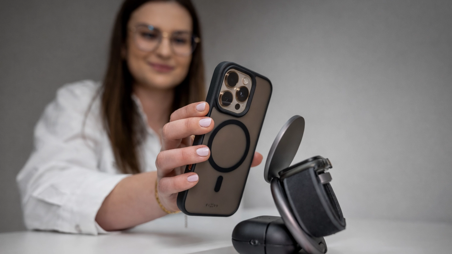 Žena přikl&aacute;d&aacute; mobil s krytem FIXED na bezdr&aacute;tovou nab&iacute;ječku