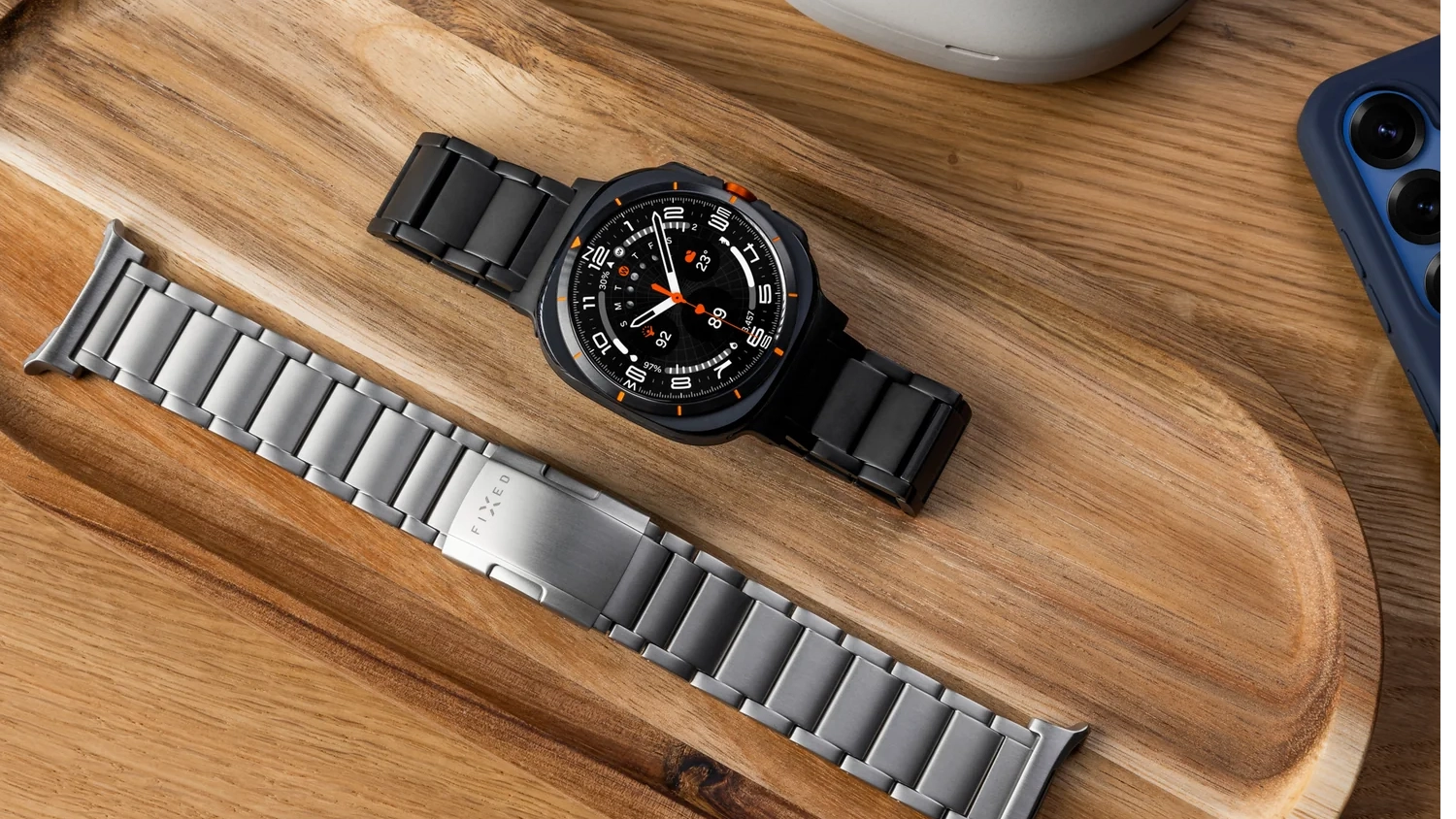 Řem&iacute;nek na hodinky Fixed Titanium Strap pro Samsung Galaxy Watch Ultra v čern&eacute;m a stř&iacute;brn&eacute;m proveden&iacute; na stole
