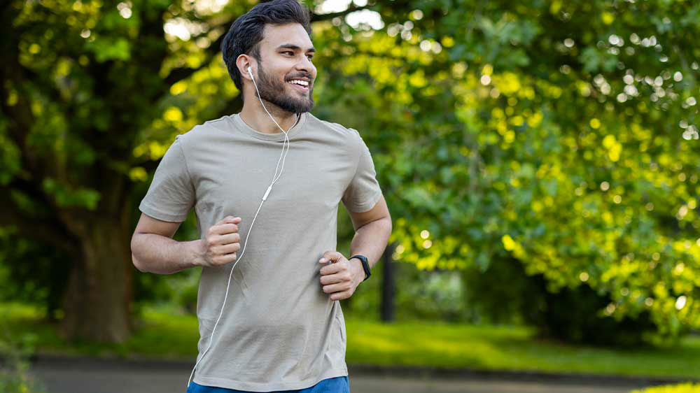 Muž běž&iacute;c&iacute; př&iacute;rodou se sluch&aacute;tky a chytr&yacute;m n&aacute;ramkem na ruce _02