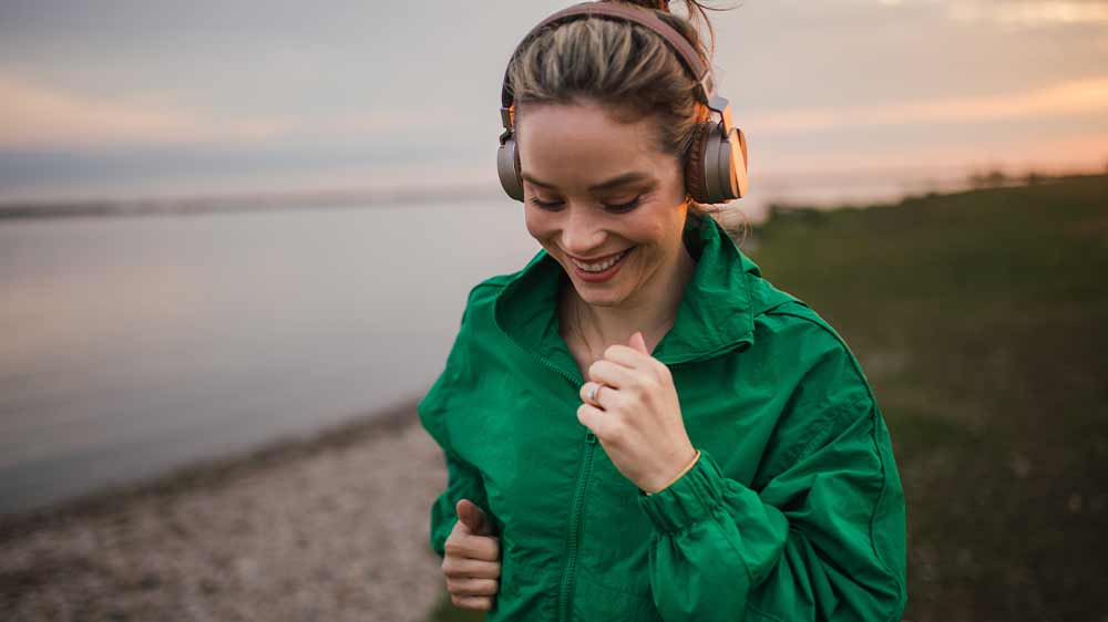 Žena se sluchátky na uších běží přírodou_05