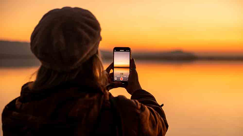 Žena fotiaca z&aacute;pad slnka mobiln&yacute;m telef&oacute;nom_04