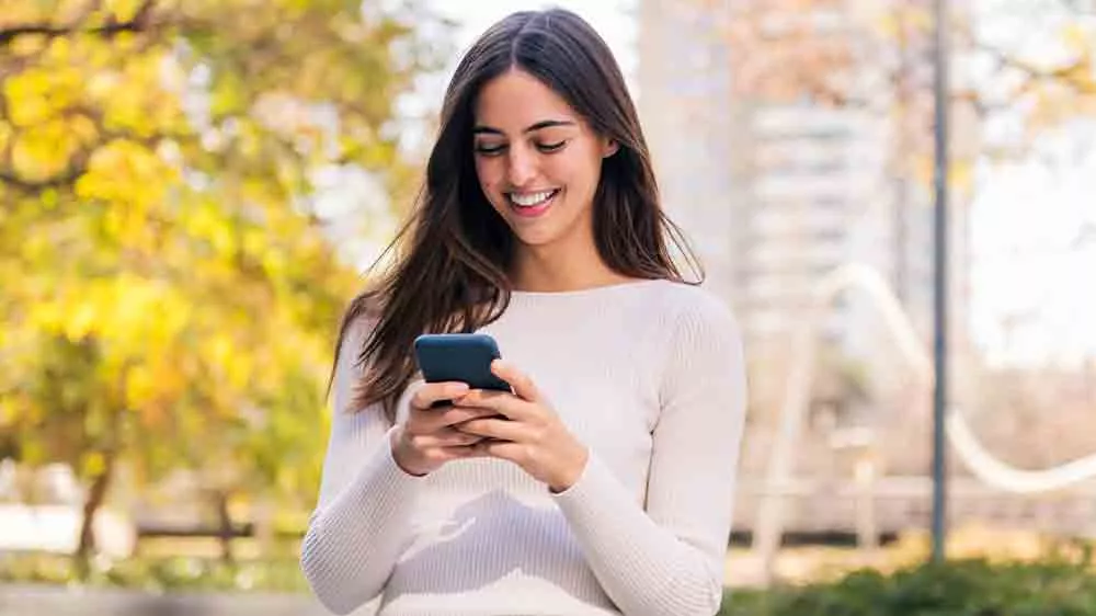 Usm&iacute;vaj&iacute;c&iacute; se žena s mobiln&iacute;m telefonem v ruce v př&iacute;rodě_02