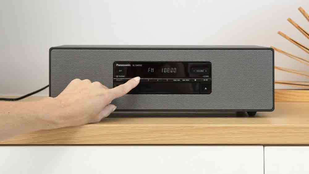 Prst ruky lad&iacute;c&iacute; stanice na mikrosyst&eacute;mu Panasonic SC-DM502E-K, kter&yacute; stoj&iacute; na skř&iacute;ňce_02