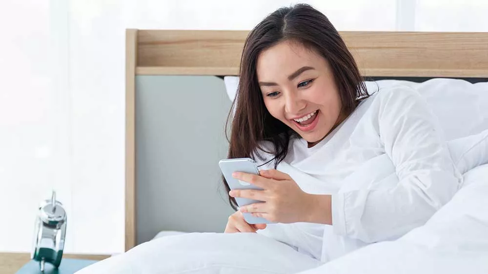 Žena se s úsměvem probudila a sleduje v mobilu údaje o svém spánku_04