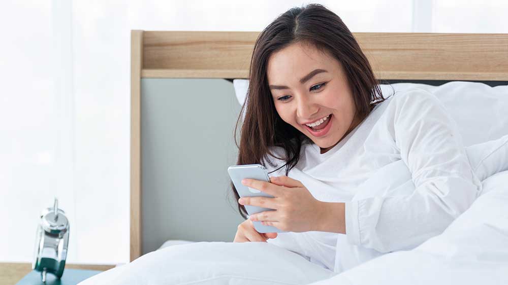 Žena se s úsměvem probudila a sleduje v mobilu údaje o svém spánku_04