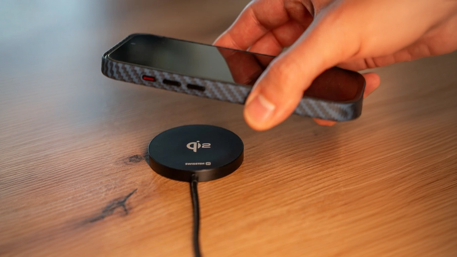 Ruka přikl&aacute;d&aacute; mobil na bezdr&aacute;tovou nab&iacute;ječku SWISSTEN MagPuck Qi2