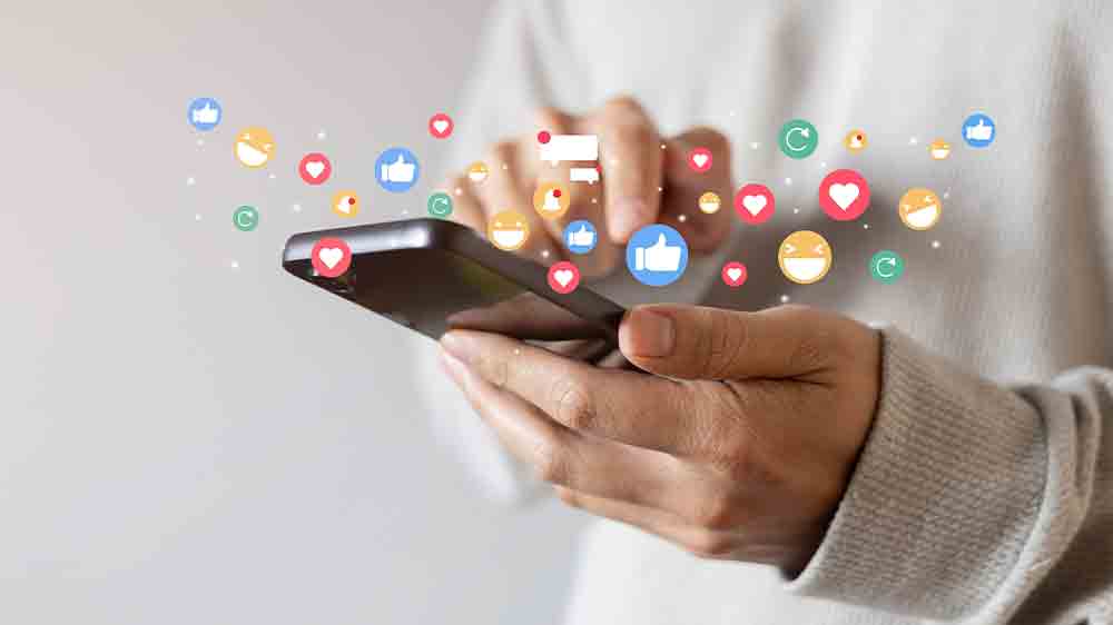 Dospělý člověk držící smartphone v ruce s emotikony okolo_03