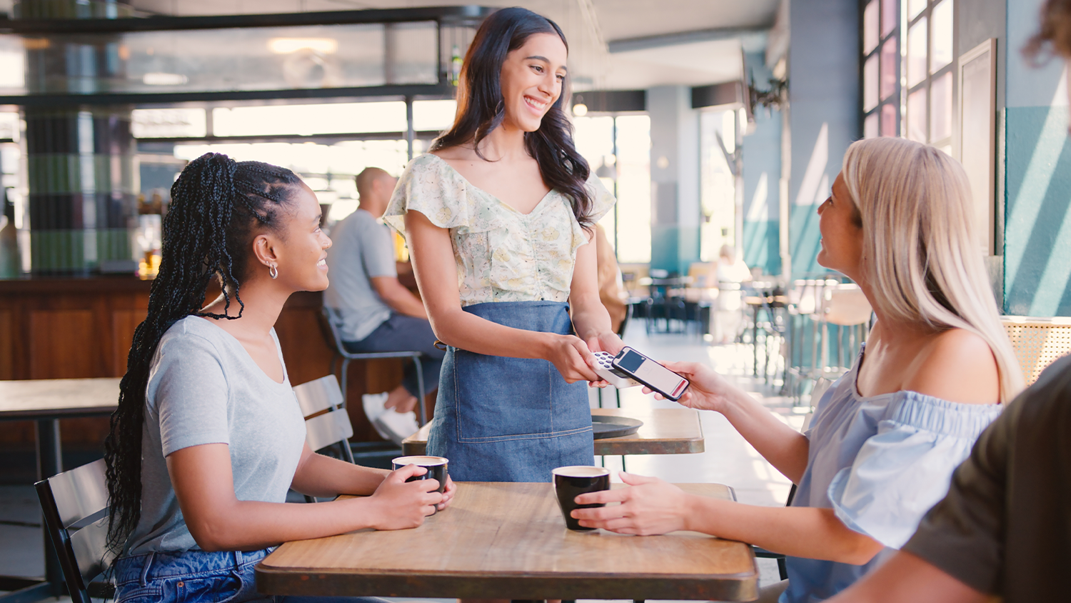 Žena platí v restauraci pomocí Apple Pay