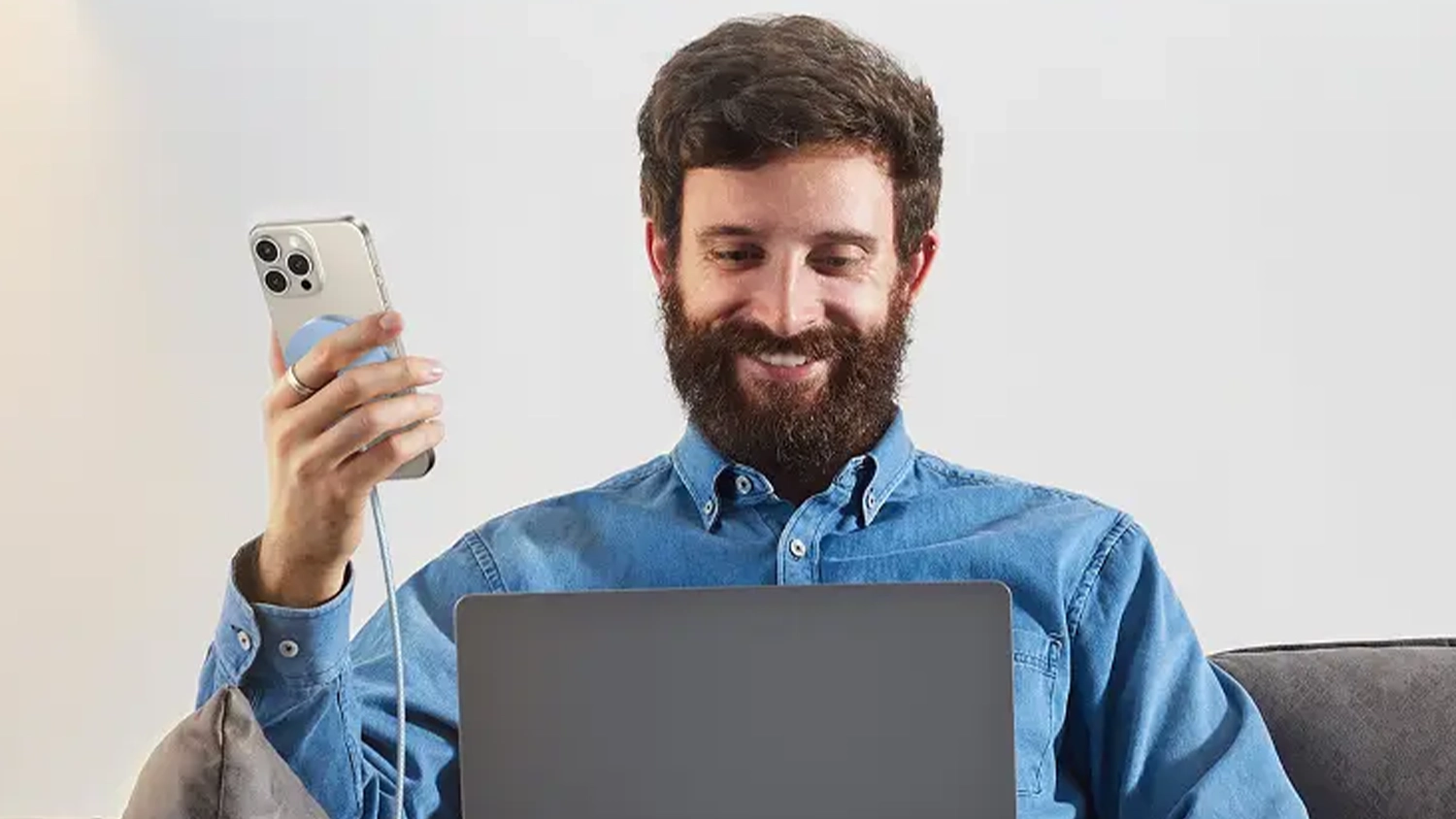 Muž s notebookem nabíjející telefon