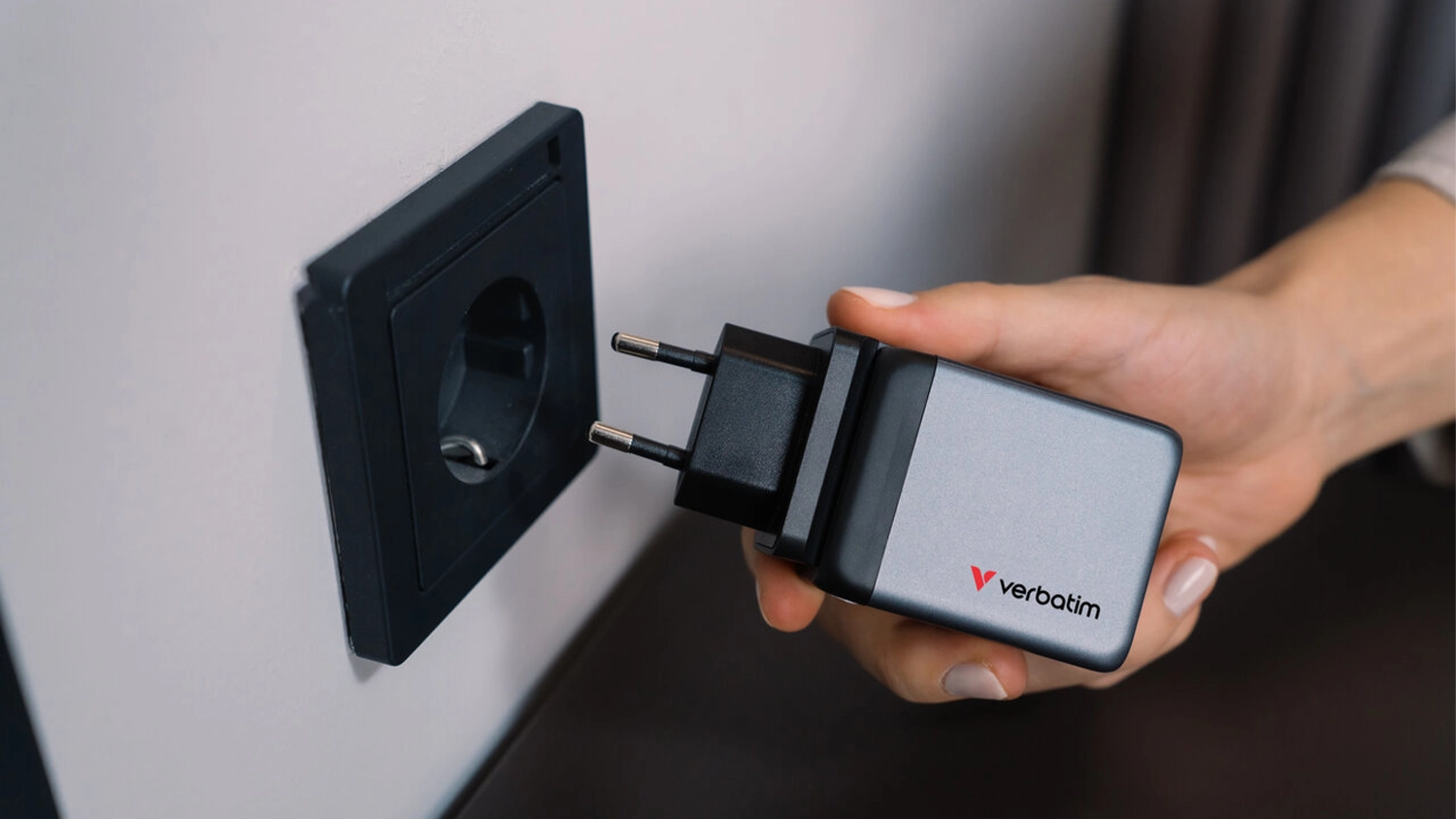 Ruka zapojuje cestovní adaptér Verbatim GaN 2xUSB-C 65W/USB-A 3.0 do zásuvky