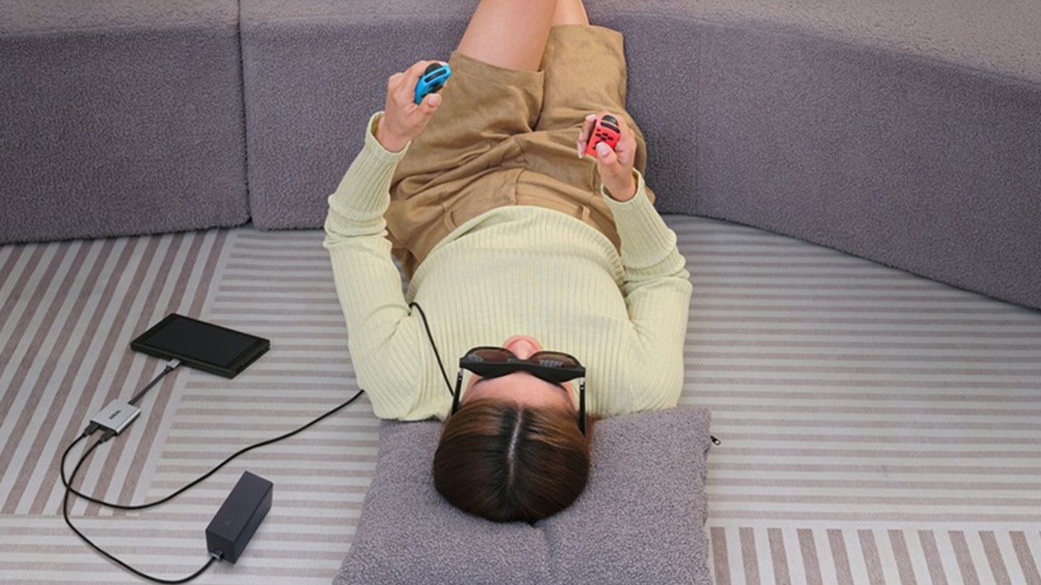 Žena s AR brýlemi na očích, připojené k napájecímu adaptéru XREAL Hub