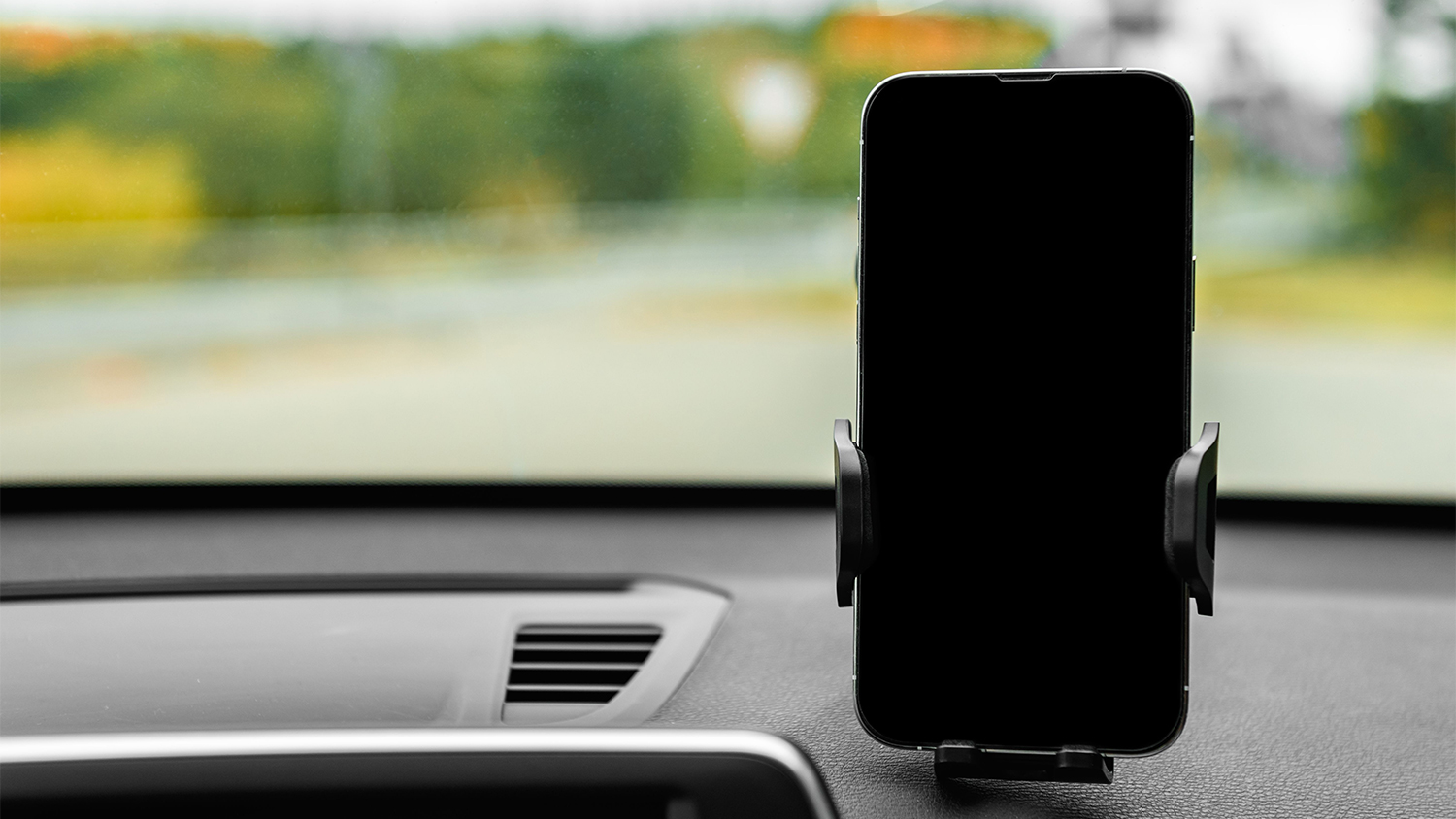 Drž&aacute;k telefonu Yenkee YSM 415 namontovan&yacute; na palubn&iacute; desce s uk&aacute;zkou automatick&eacute;ho up&iacute;nac&iacute;ho mechanismu