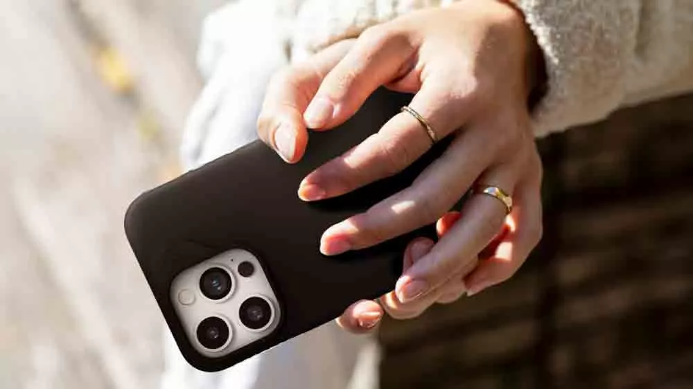 Ženské ruce držící iPhone 15 PRO v krytu ZAGG Manhattan Snap BK_02