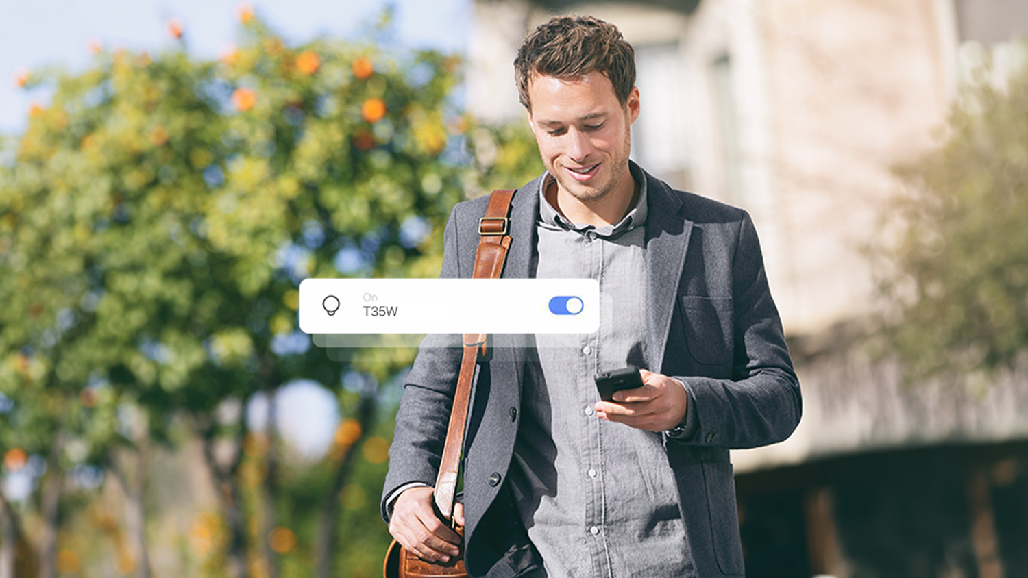 Muž s mobilem v ruce řídící světla v domě pomocí aplikace