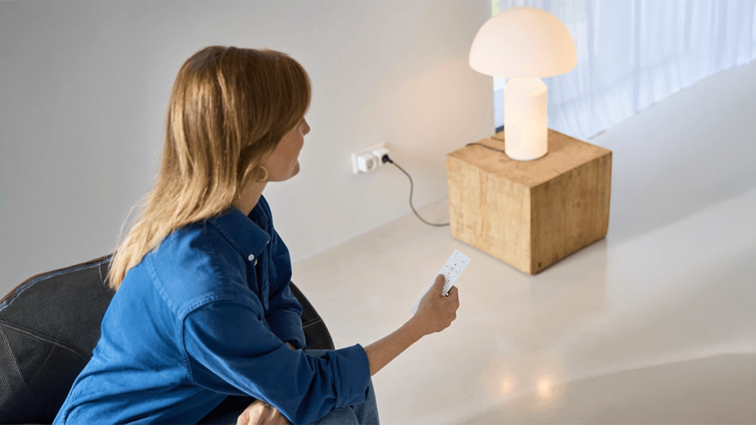 Žena ovládá chytrou zásuvku Trust Smart Wi-Fi pomocí ovladače