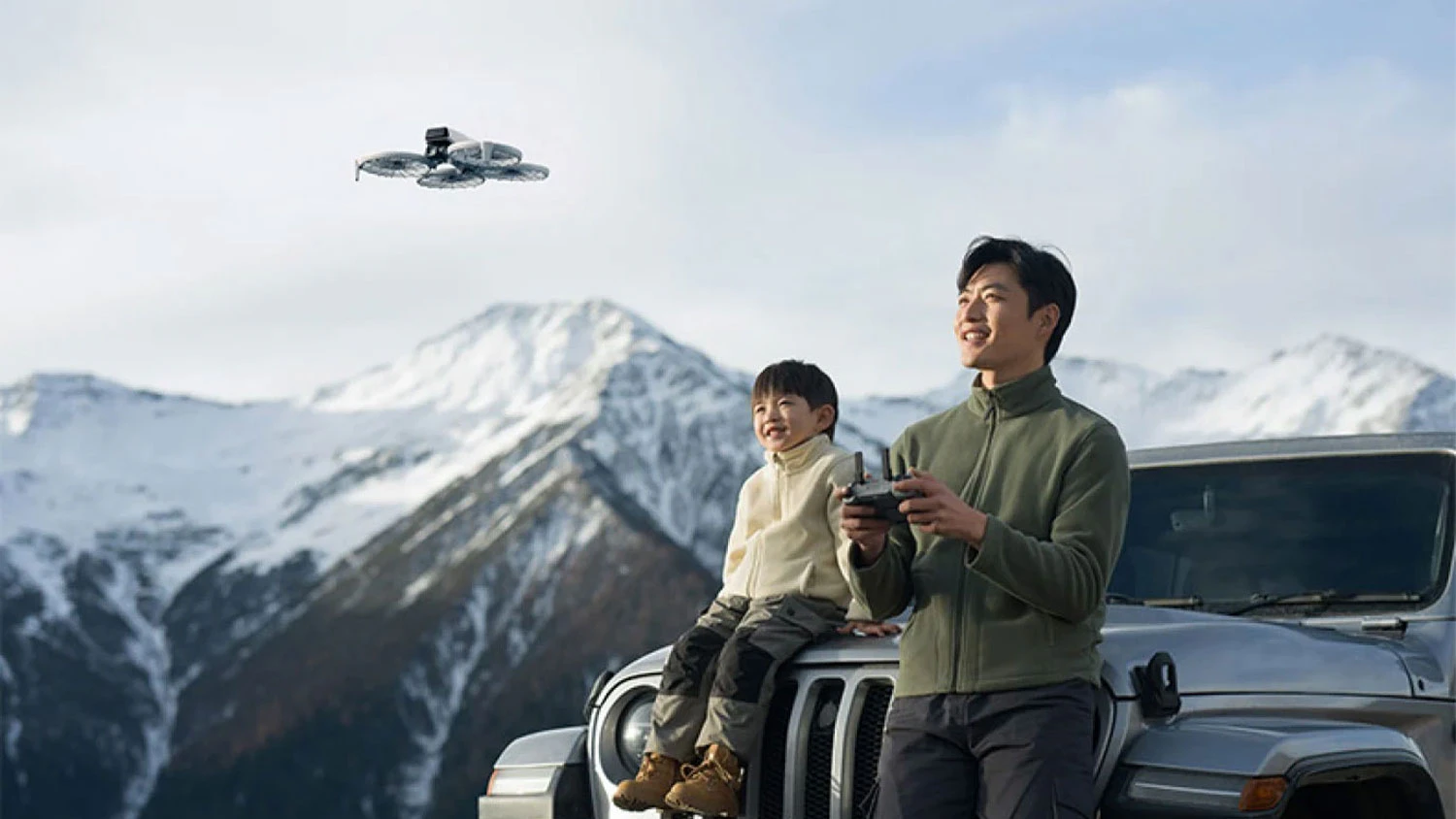 Muž a dítě v horách u auta s dronem DJI Flip