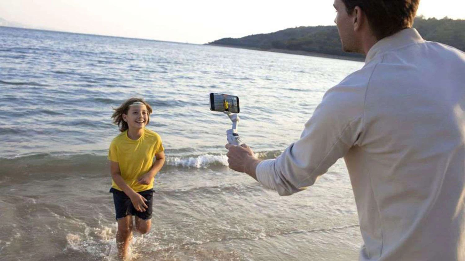 Muž natáča dieťa mobilom umiestneným na stabilizátore DJI Osmo Mobile 7