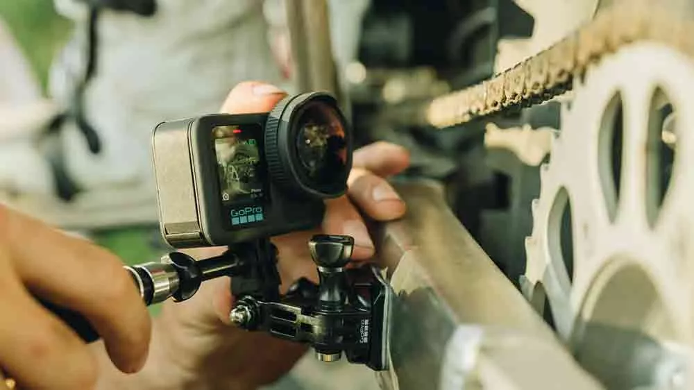 Ruce drž&iacute;c&iacute; kameru GoPro s nasazen&yacute;m objektivem GoPro HB v těsn&eacute; bl&iacute;zkosti řetězu kola _04