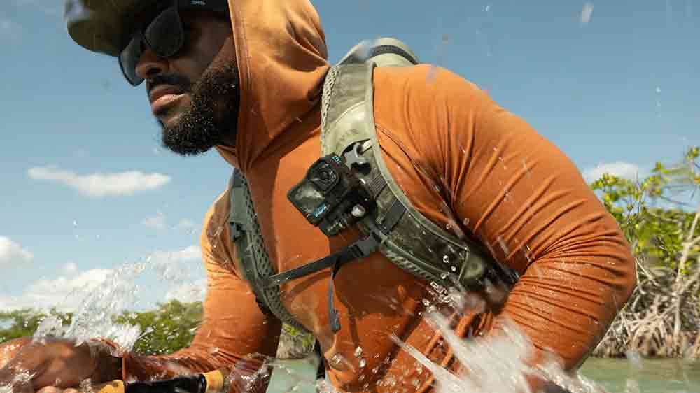 Muž ve vodě s batohem na zádech a připevněnou outdoorovou kamerou GoPro Hero13 Black na ramenním popruhu batohu_04