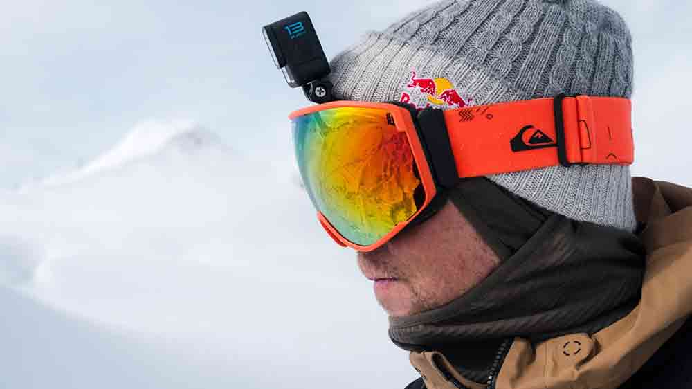 Muž v lyžařském oblečení na horách s upevněnou outdoorovou kamerou GoPro Hero13 Black za nasazenými lyžařskými brýlemi_05