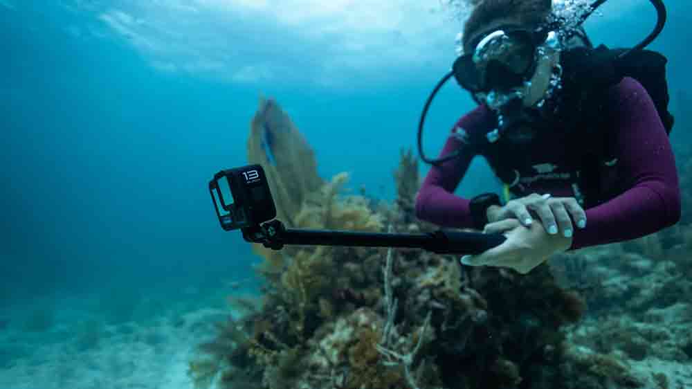 Žena potápěčka držící v ruce outdoorovou kameru GoPro Hero13 Black nasazenou na dlouhé rukojeti_06