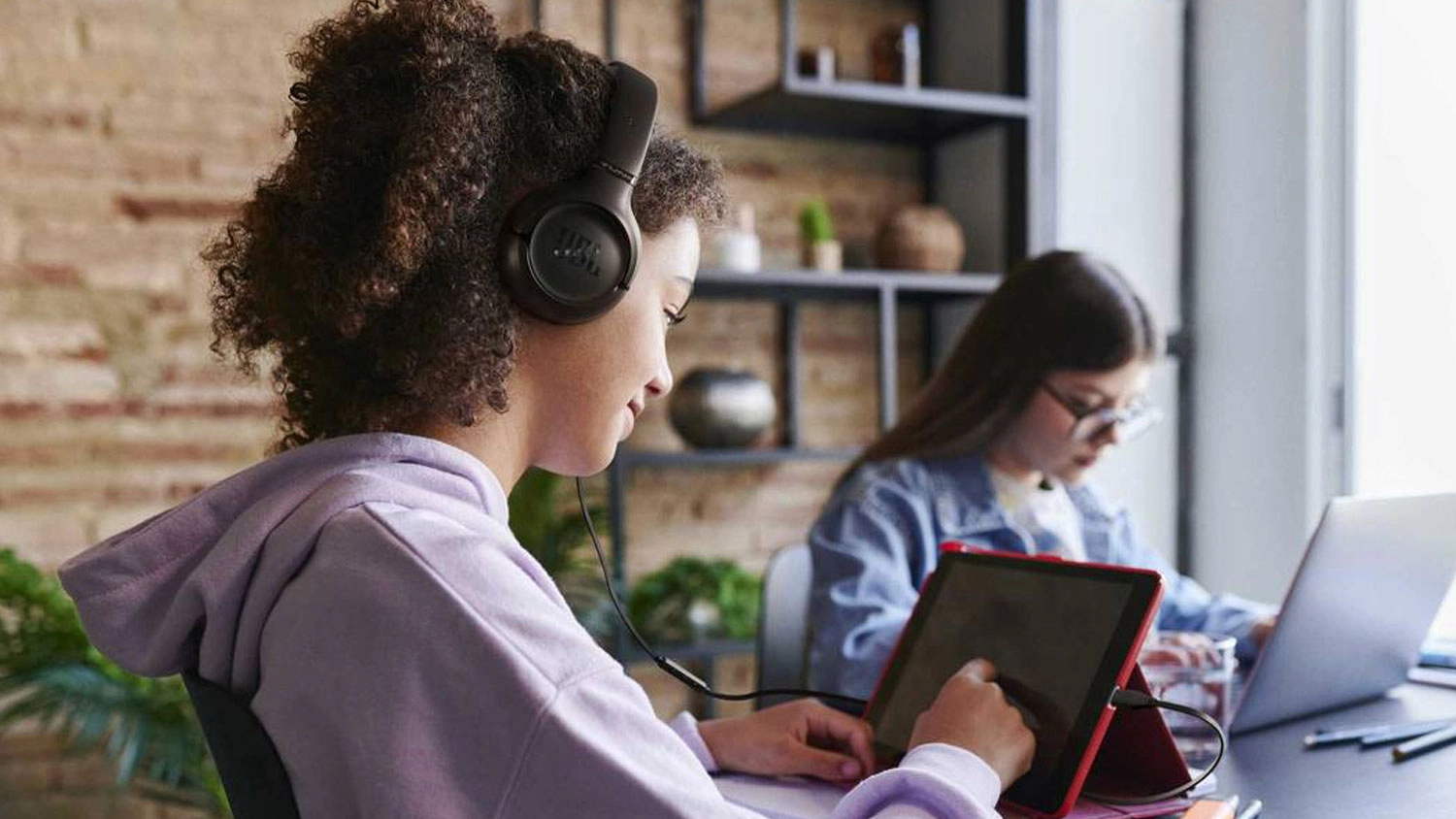 Žena pracuje na tablete so slúchadlami JBL Tune 530C na hlave.
