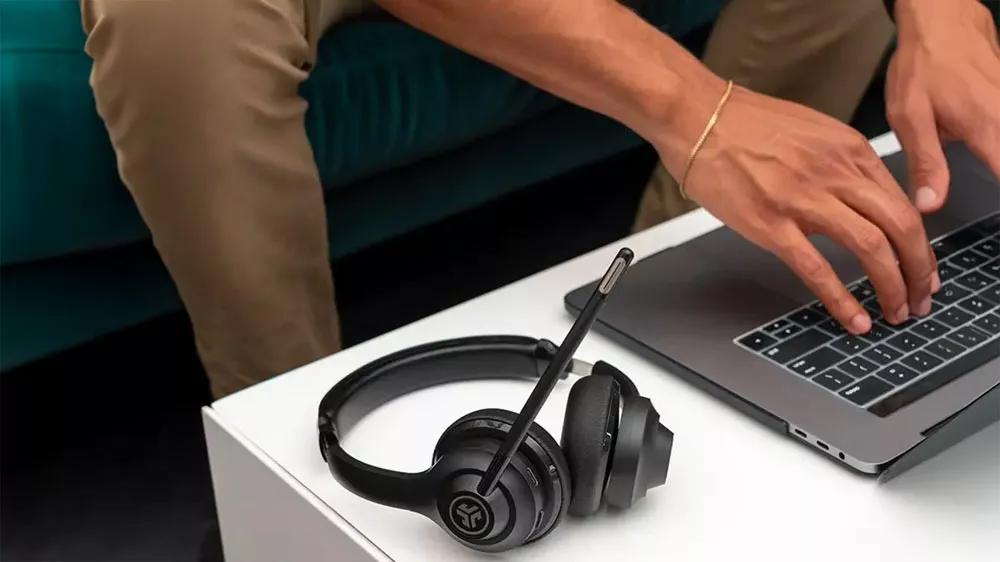 Sluch&aacute;tka JLab GO Work položen&aacute; na stole vedle poč&iacute;tače_03