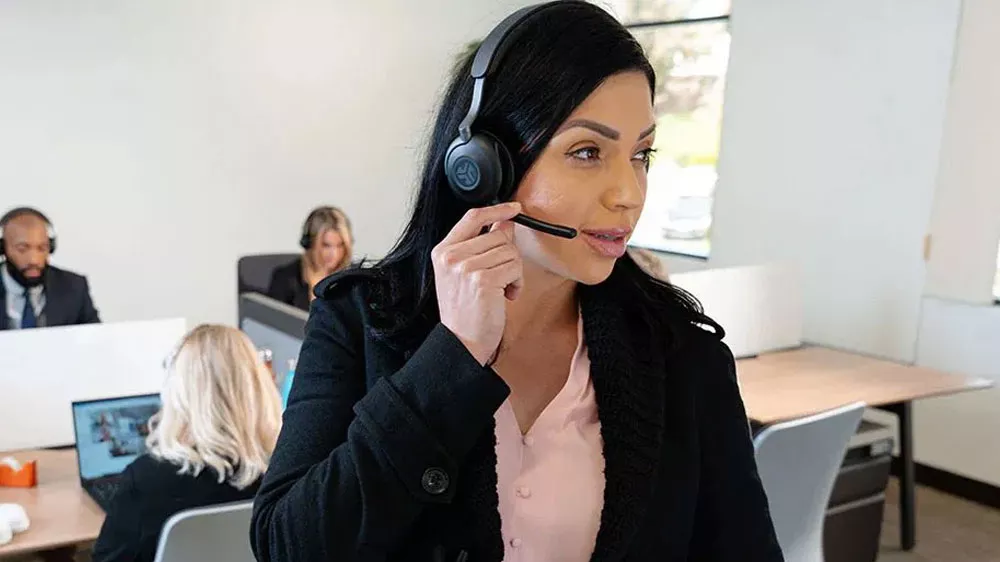 Žena telefonující s JLab Epic Work s pozadím kanceláře_03
