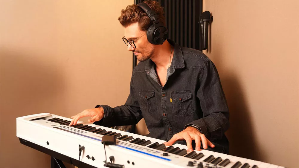 Hudobník v štúdiu hrá na klávesy s bezdrôtovými DJ slúchadlami OneOdio Studio Max 1 na ušiach_02
