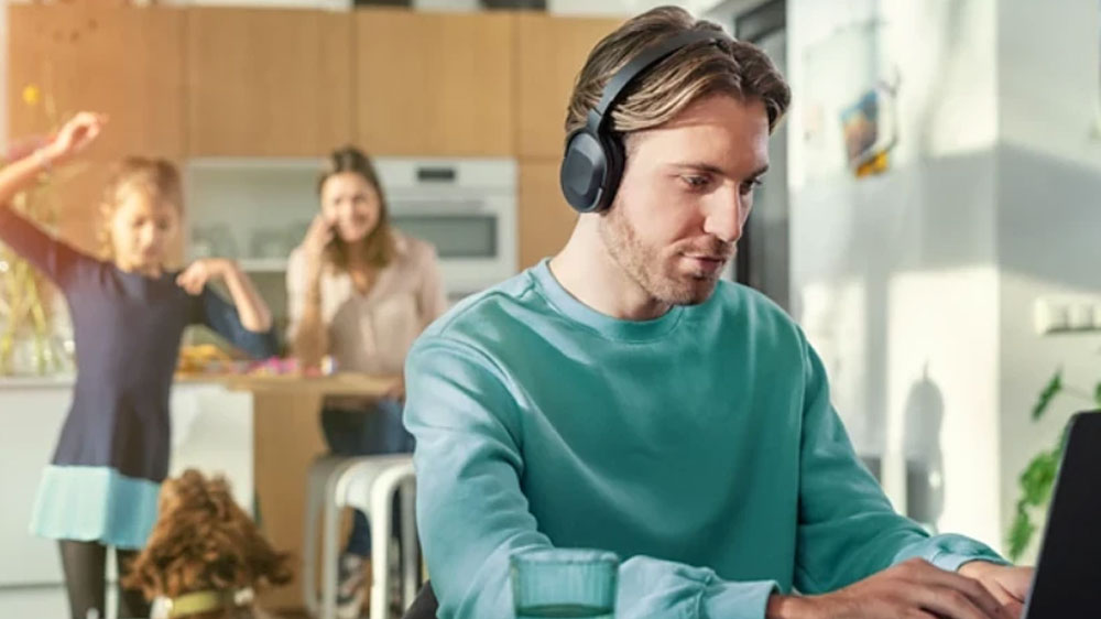Muž pracuj&iacute;c&iacute; na poč&iacute;tači se sluch&aacute;tky Philips TAH6506BK/00 na hlavě_02